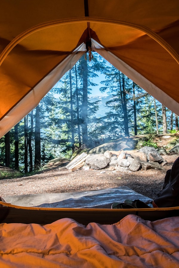 Tienda de camping iluminada al atardecer en montaña